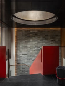 A hotel lobby staircase with red brick stairs, stone walls, and warm lighting creating a cozy atmosphere
