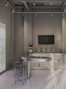 Industrial-style bar with a large metal countertop, beer taps, and stools, set in a modern and functional space