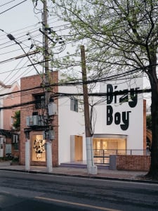 A brick building with a large white wall featuring graffiti, surrounded by people and bicycles