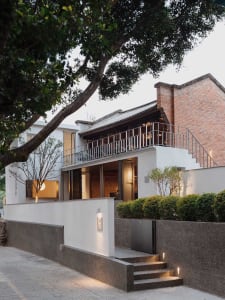 A rendered image of a house with a white exterior, a brick wall, and a red roof, featuring a patio area and conveying a sense of warmth and comfort