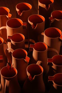 A table filled with various sized orange ceramic cups, creating a warm and inviting atmosphere