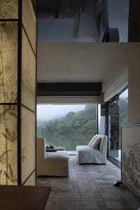 Comfortable living space with a couch, chair, and table in front of a large window, adorned with Asian artwork and well-lit
