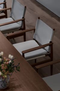 Empty dining area with a wooden table and six chairs, a vase on the table, and warm lighting
