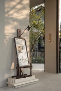 A framed artwork on a wooden stand in front of a building, adding a creative touch to the urban environment