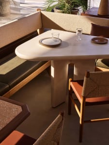A modern dining area with a large white table surrounded by multiple chairs, set up for a meal in a clean and inviting environment