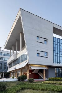 A modern building with a gray exterior, glass walls, and multiple windows and balconies, featuring a staircase and contemporary architecture