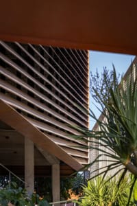 A modern high-rise building with a concrete exterior and large windows, set against a backdrop of palm trees in an urban environment