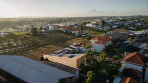 Aerial view of a residential area with a mix of traditional and modern houses, buildings, and a field, featuring parked cars and a truck in a calm and peaceful atmosphere