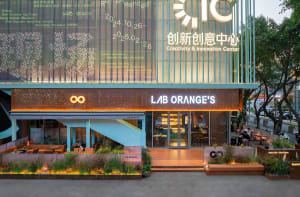 Lively retail space with orange walls, a large window display, and various objects on display, surrounded by people