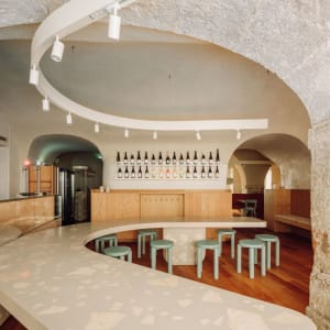 Inviting bar area with a curved counter, stools, wine bottles, cups, and bowls, set in a comfortable and social atmosphere