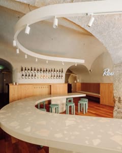 A restaurant bar with a curved countertop, chairs, and bottles, creating a welcoming atmosphere for socializing and dining