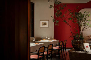 Dining area with a red accent wall, a table, chairs, and wine glasses, creating a sophisticated and inviting atmosphere