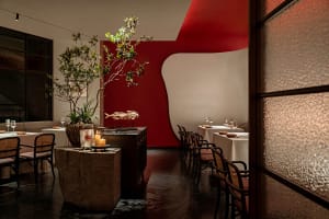 Cozy restaurant interior with red walls, white accents, and potted plants, creating a warm and inviting atmosphere
