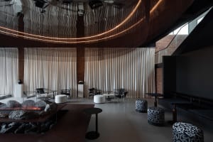 Comfortable modern dining space with a large table, couches, and a fireplace, surrounded by warm lighting