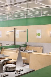 Empty restaurant interior with wooden walls, green accents, and dining tables and chairs