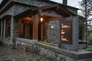 A stone building with a wooden structure and a large archway, featuring signs and a blend of traditional and modern architectural elements