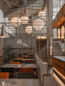 A modern restaurant with a large dining area featuring several tables and chairs, creating an inviting atmosphere for socializing and meals