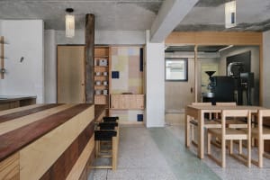 Modern kitchen with wooden floors and walls, featuring a dining table and chairs, with cups on surfaces, conveying a clean and organized atmosphere with a focus on functionality and aesthetics