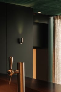 A casual home bar scene with a sink on the left and a beer tap on the right, accompanied by two bottles