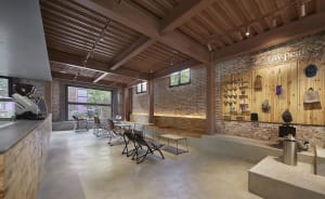 Cozy living area with a brick building, a dining table, potted plants, and scattered bottles, creating a warm and inviting atmosphere