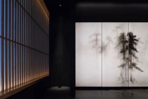 A serene room with a tree mural on the wall, a vase, and a calm atmosphere