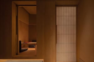 A modern living space with wooden walls and floors, featuring two couches and a chair, giving off a cozy and comfortable atmosphere