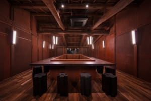 A restaurant and bar area with wooden paneling, dining tables, chairs, and lighting fixtures creating a warm and inviting atmosphere