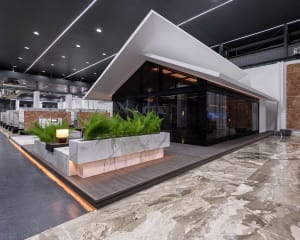 A modern house with a glass wall, potted plants, and two chairs, conveying a sense of contemporary design and comfort