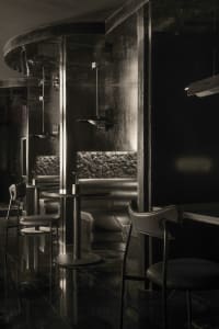 Elegant restaurant interior with multiple dining tables, chairs, a bar, and couches, featuring a black and white color scheme