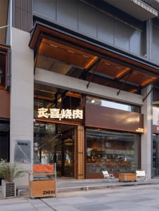 A modern Asian restaurant with wooden paneling, chairs, and dining tables, flooded with natural light through a large window