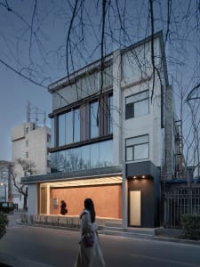 Architectural rendering of a modern building with a large glass wall, multiple levels, and a concrete structure, set against a neutral background