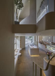 Open modern kitchen and dining area with natural light, a large window, a counter, sink, dining table, chairs, and potted plants