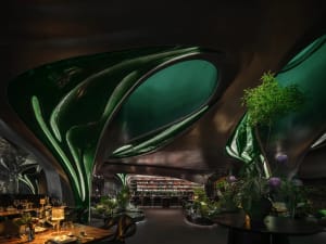 A modern restaurant with green and purple tile walls, potted plants, and a comfortable atmosphere