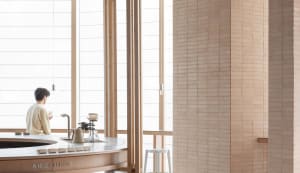 Open kitchen space with wooden floors and walls, featuring two sinks, a dining table, and various decorative items