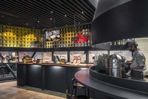 Modern restaurant interior with a black countertop, yellow accents, and seating for customers
