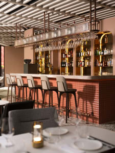 A modern bar area with a long counter, red and gold accents, and seating for patrons