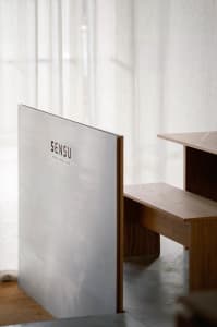 Cozy interior space with a wooden bench, chairs, and a sign on the wall