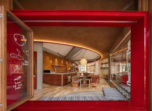 Open living area with wooden floors and walls, featuring a combined kitchen, dining, and living space with comfortable seating and dining table