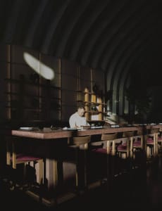 A restaurant dining area with a long wooden table surrounded by multiple chairs, creating a warm and inviting atmosphere for patrons
