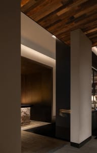 Dining area with wooden walls and floors, featuring a dining table and a kitchenette with a sink, with a warm and inviting atmosphere
