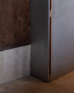 A modern interior space with a steel door and a brown wall with a tiled surface