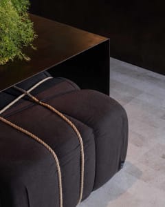 A well-lit living area with a black couch and rope detail on a hardwood floor