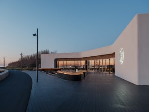A modern restaurant interior with a curved design, featuring dining tables and chairs in a stylish environment