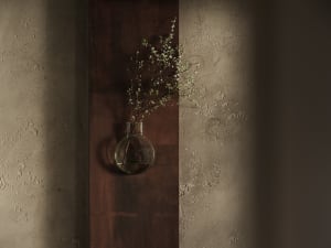 A wooden wall with a vase containing flowers hanging on it, adding a touch of nature to the space