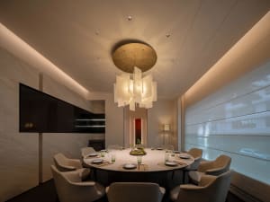A dining area with a round table set with various items, surrounded by chairs, creating a sophisticated and comfortable environment for socializing and dining