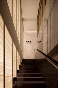 A well-lit stairwell with wooden stairs and black railings, possibly in a hotel or office building