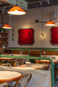 Warm and inviting Asian restaurant with wooden tables, red signs, and cozy lighting