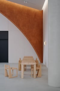 A modern dining space with wooden tables and chairs, warm orange walls, and a cozy atmosphere