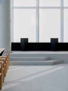 Empty minimalist room with a large window, several chairs, and a clean atmosphere
