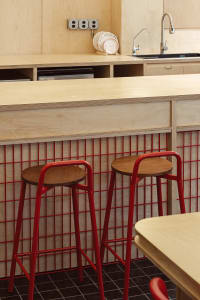 A kitchen with wooden countertops and red stools, featuring an open design and warm atmosphere with red accents